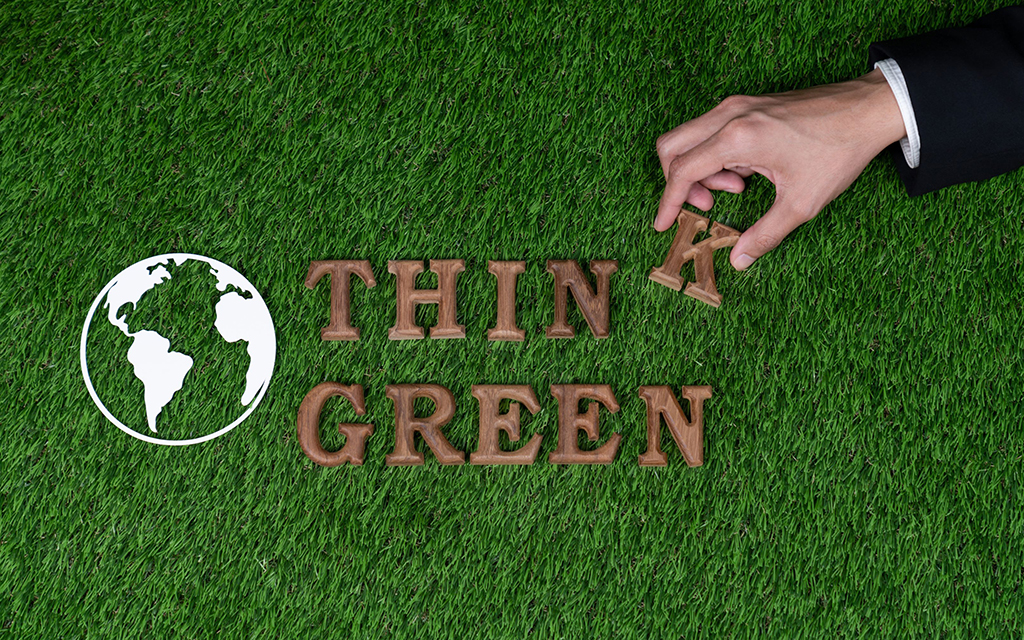 The words “think green” spelt in wooden letters over a grass floor. 